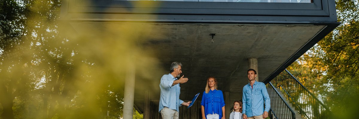 Family talking to realtor by extra modern home.