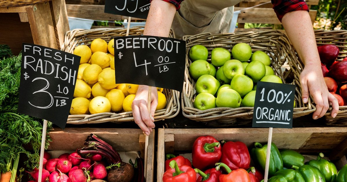 Person putting price signs on vegetables at the farmers market