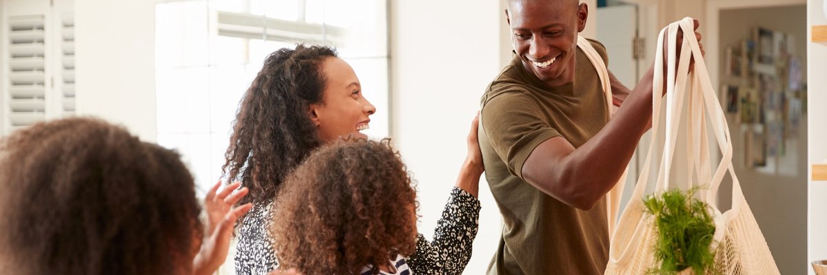 A smiling father bringing home groceries to his family.