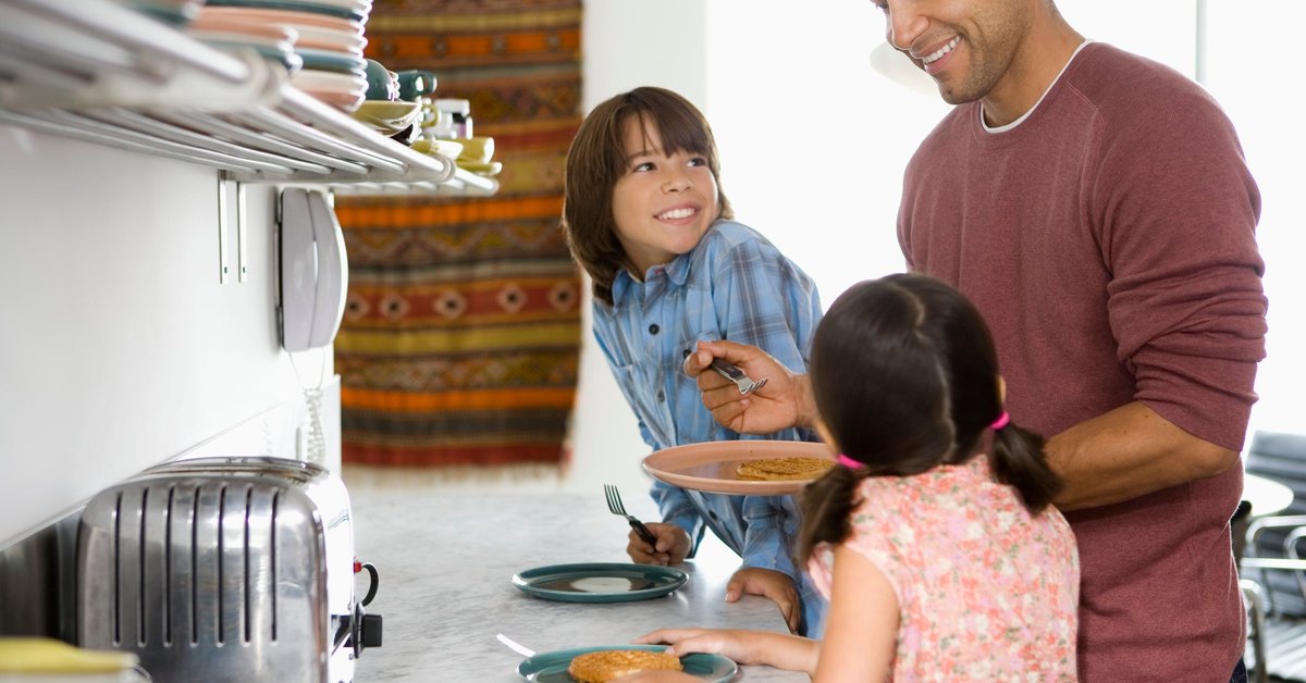 Father in kitchen with kids making breakfast