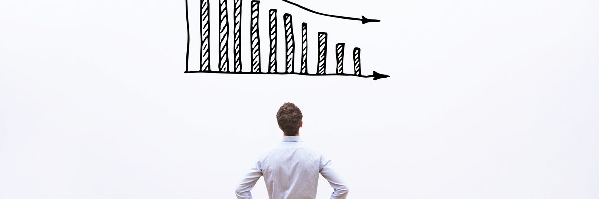 Man standing in front of a white board with a decreasing bar graph drawn on it