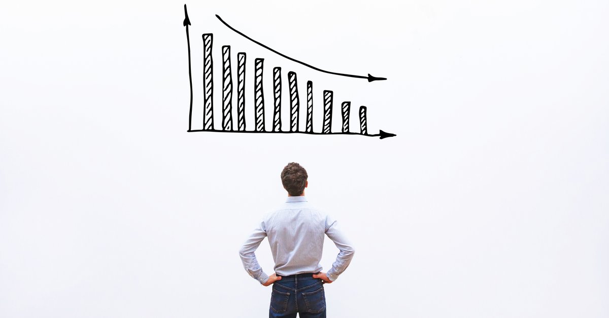 Man standing in front of a white board with a decreasing bar graph drawn on it