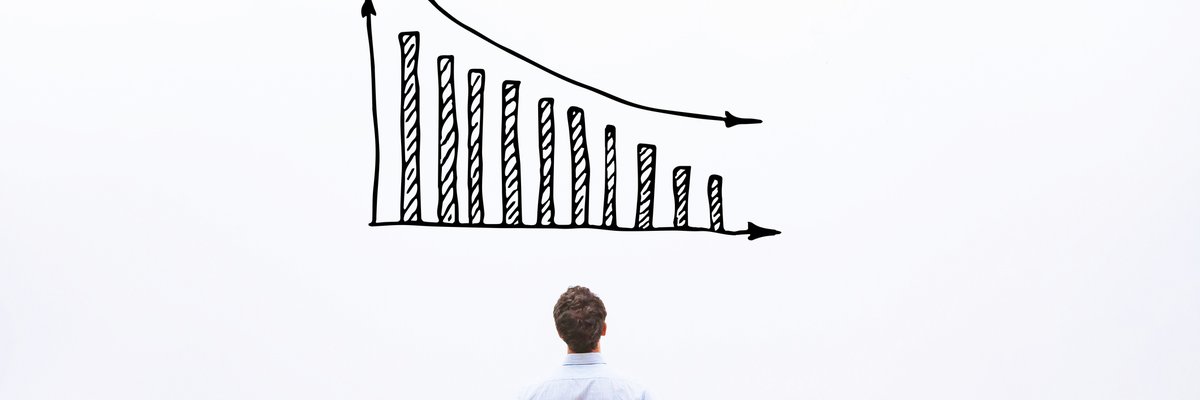 Man standing in front of a white board with a decreasing bar graph drawn on it