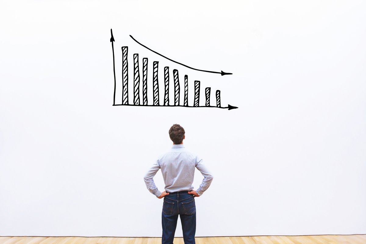 Man standing in front of a white board with a decreasing bar graph drawn on it