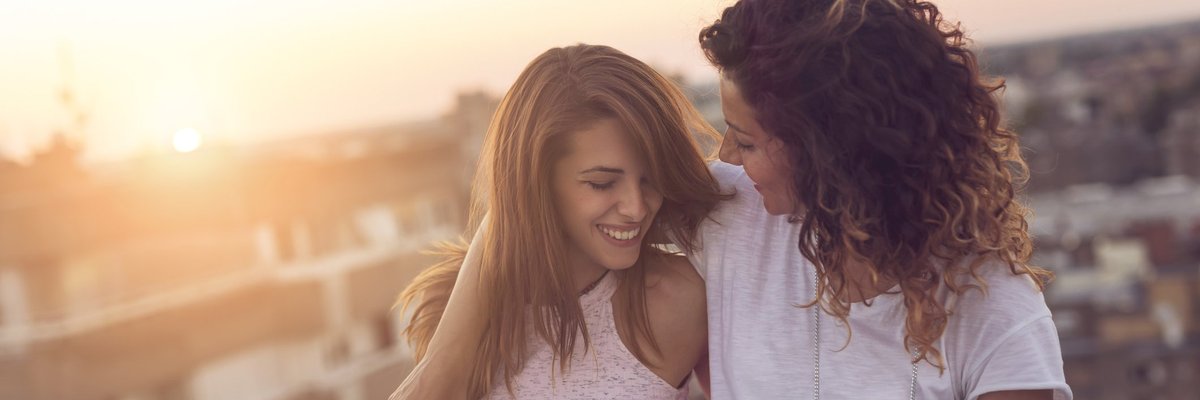 Two women smiling with their arms around each other.
