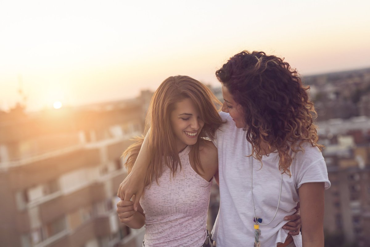 Two women smiling with their arms around each other.