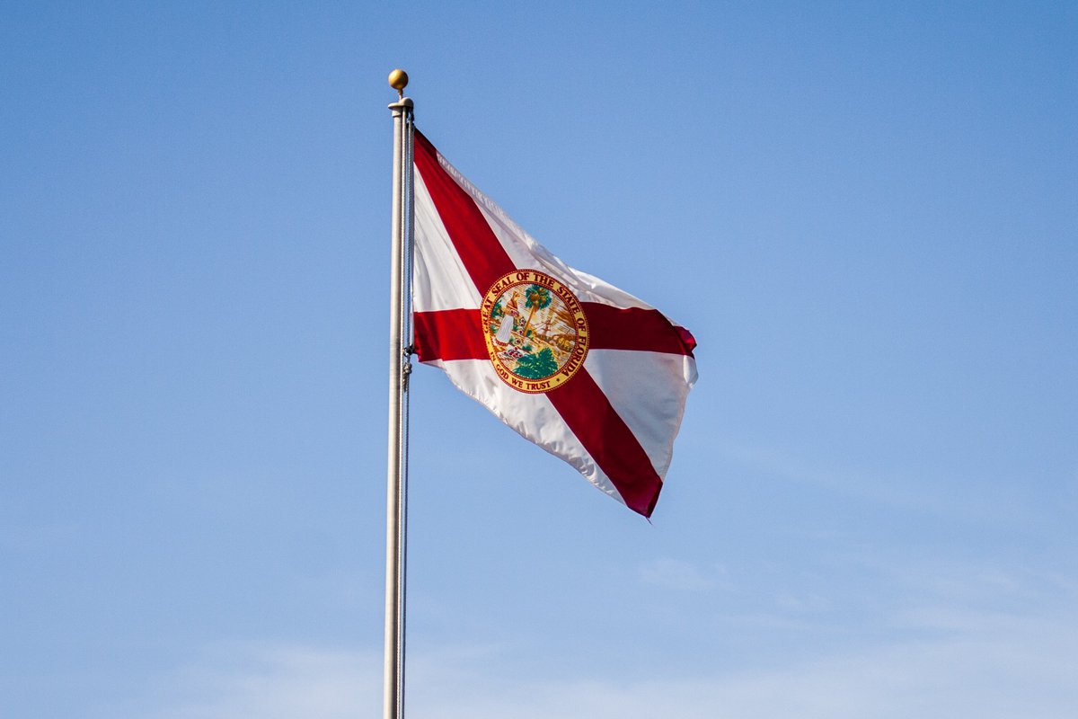 The Florida state flag flying in front of a blue sky.