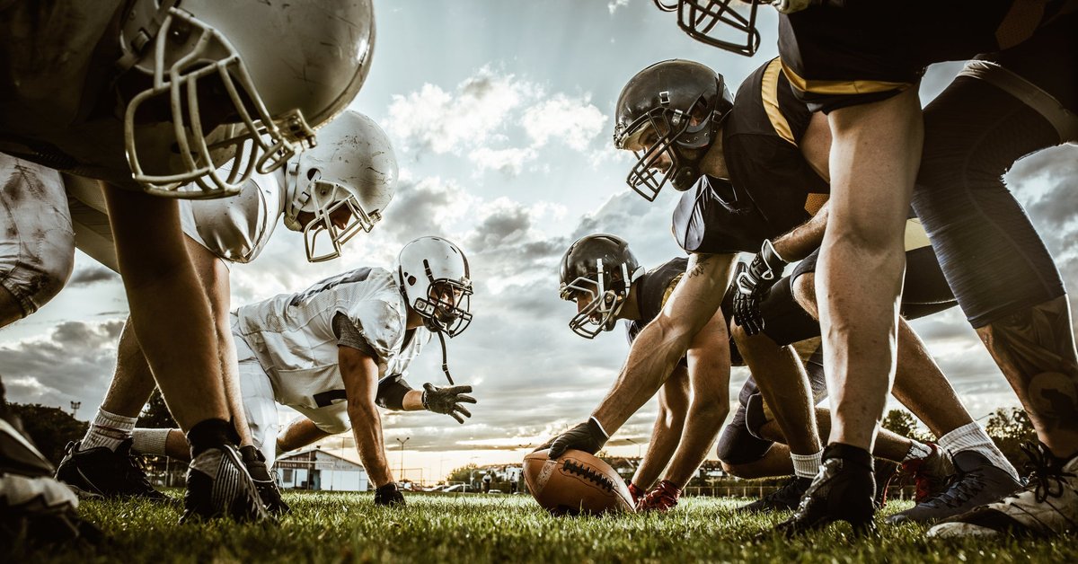 Football players face off against each other on field.