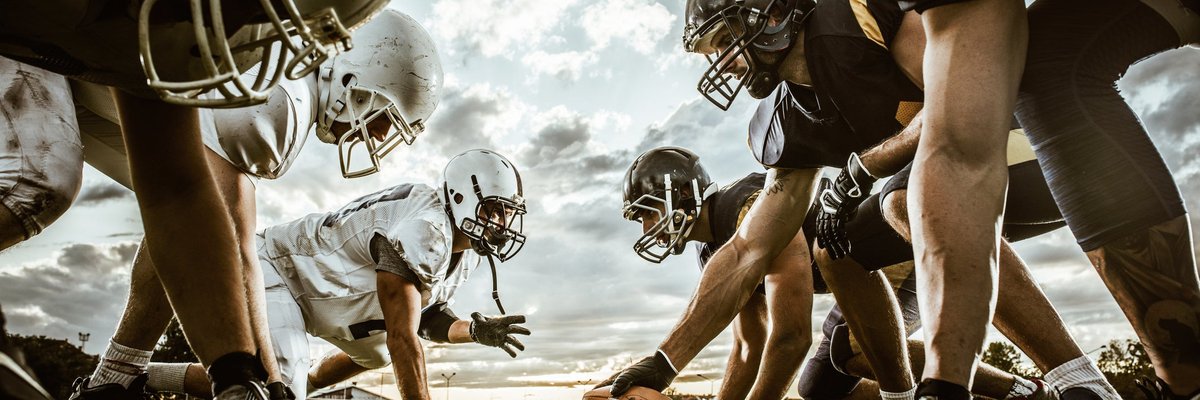 Football players face off against each other on field.
