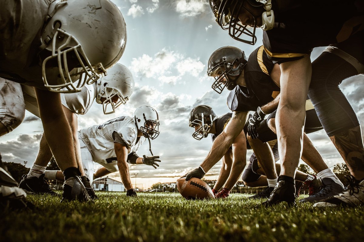 Football players face off against each other on field.