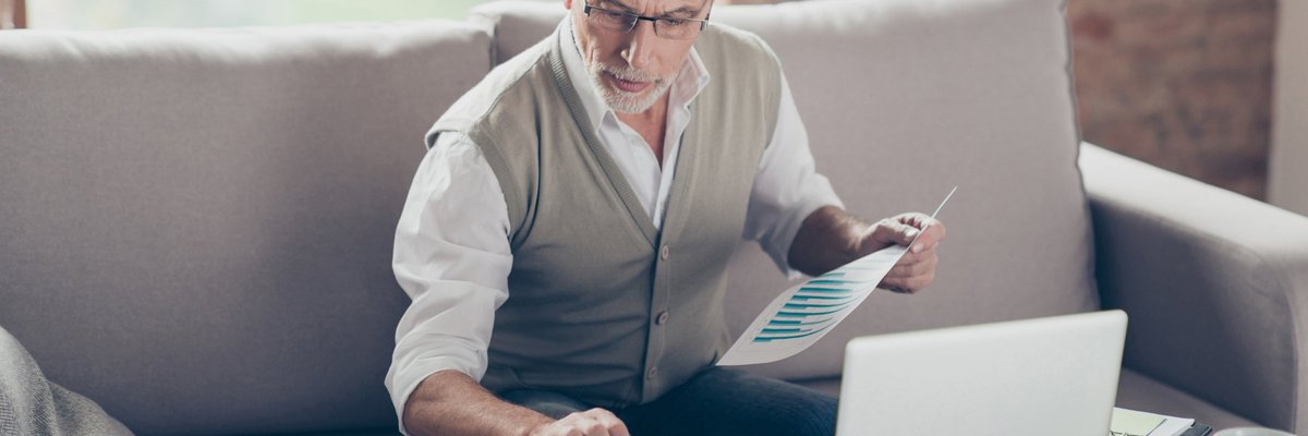 Older man using calculator and laptop.
