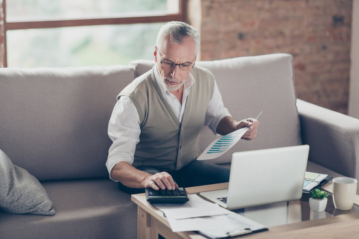 Older man using calculator and laptop.