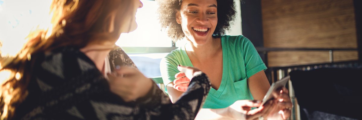 Friends looking at the mobile phone at a cafe.