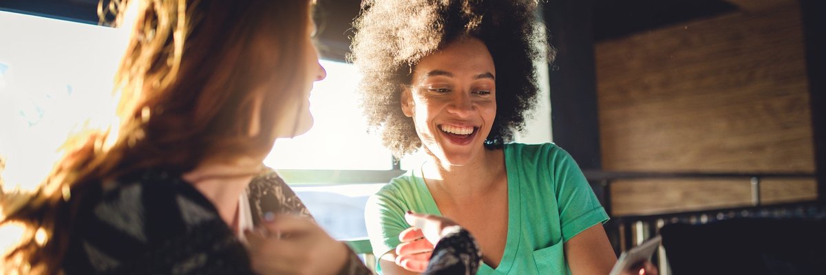 Friends looking at the mobile phone at a cafe.