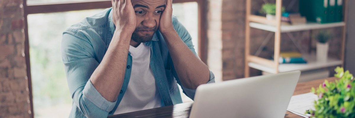 Frustrated Man At Computer With Head In Hands