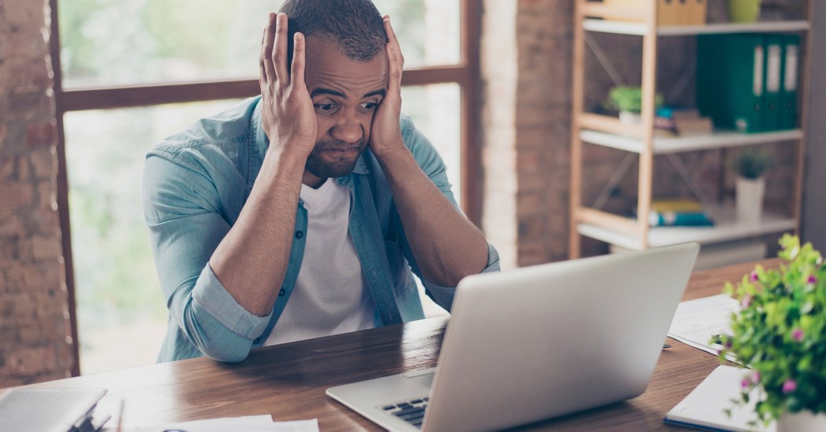 Frustrated Man At Computer With Head In Hands