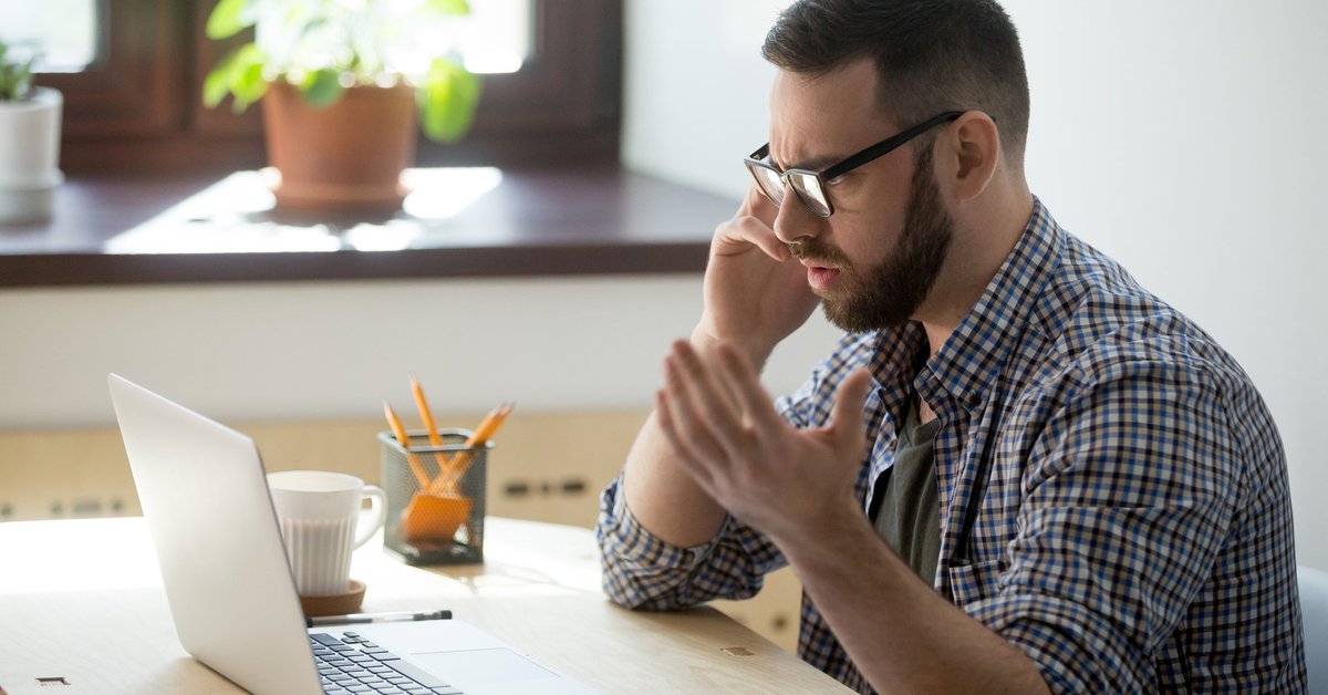 Frustrated man on phone at laptop
