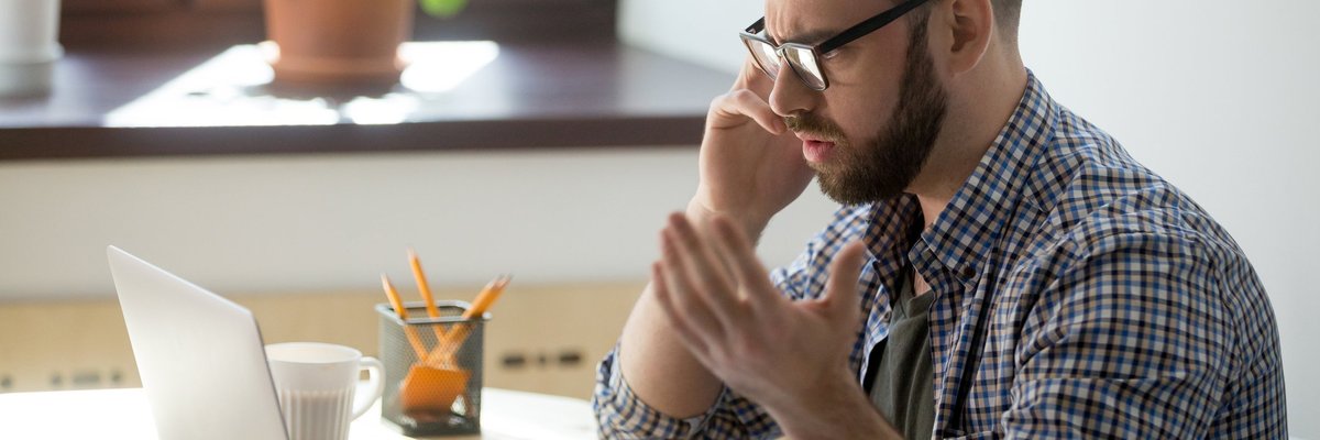 Frustrated man on phone at laptop