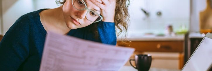 Young woman looks at her bills with a worried facial expression.