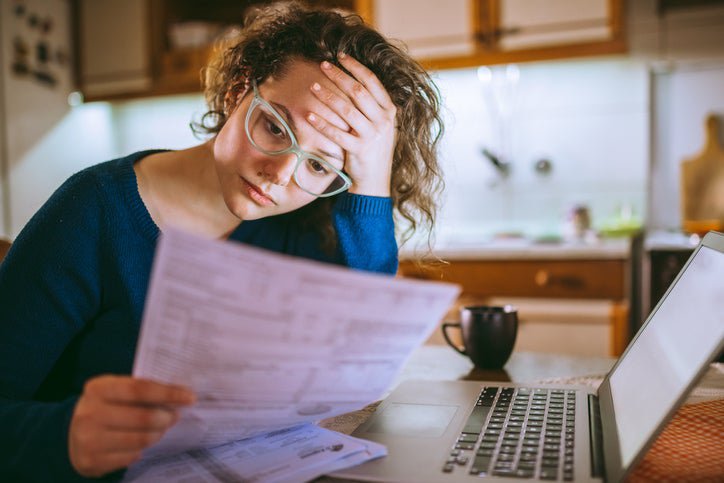 Young woman looks at her bills with a worried facial expression.