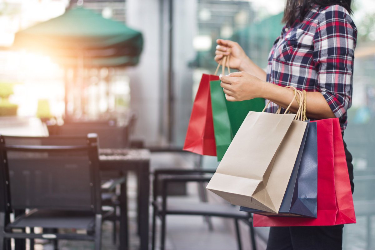Woman carrying a number of colorful shopping bags on her arms.