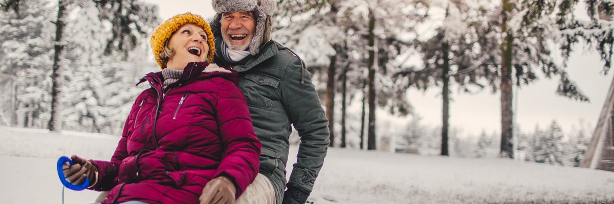Mature couple sledding together in the snow.