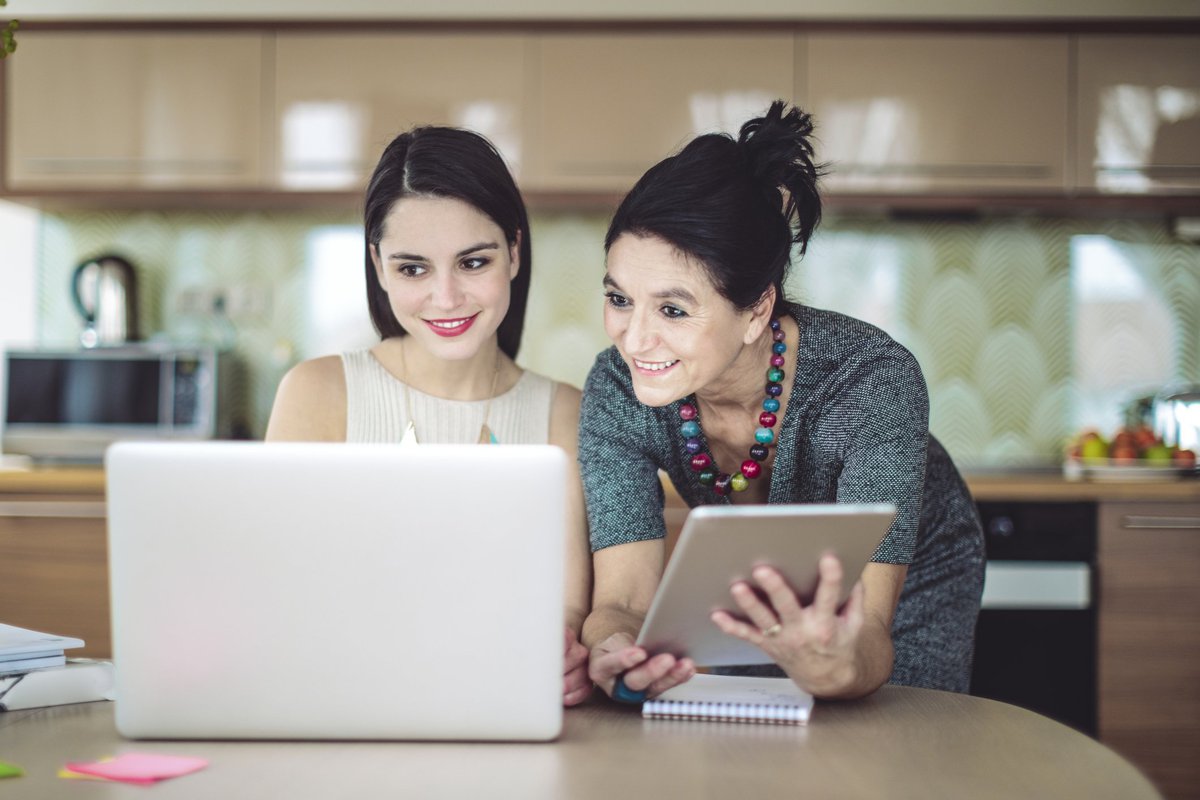Mother and daughter smiling as they go over some information together.