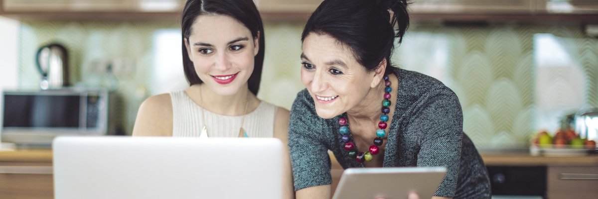 Mother and daughter smiling as they go over some information together.