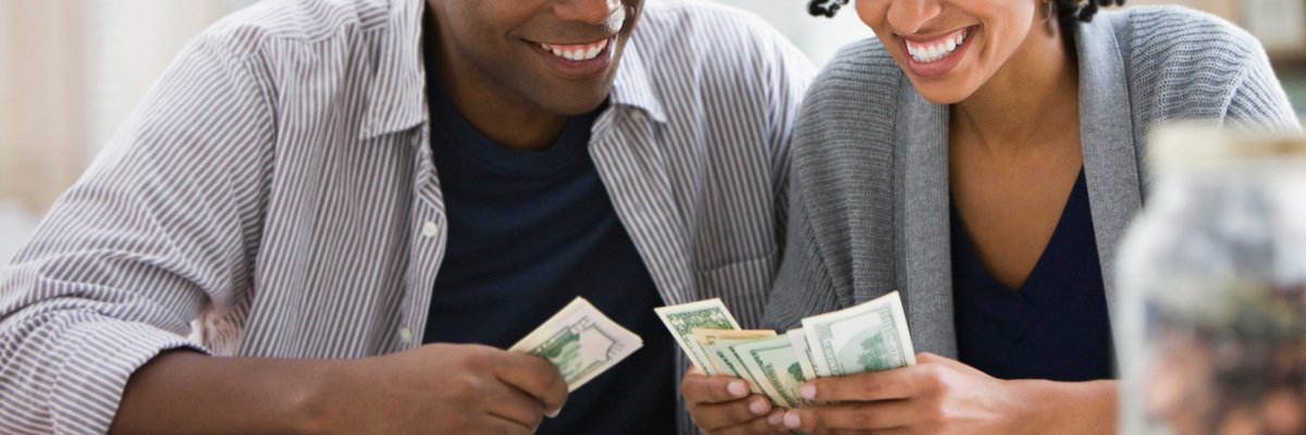 A couple counts dollar bills together at home.