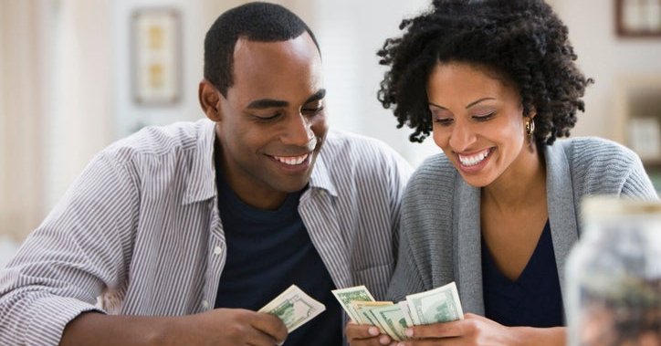 A couple counts the bills and coins they've saved in a jar.