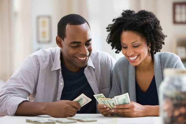 A couple counts the bills and coins they've saved in a jar.