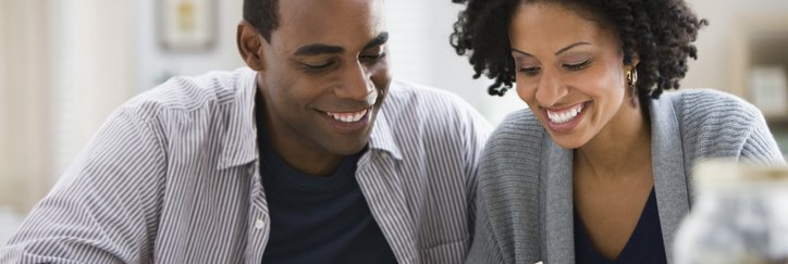 A couple counts the bills and coins they've saved in a jar.