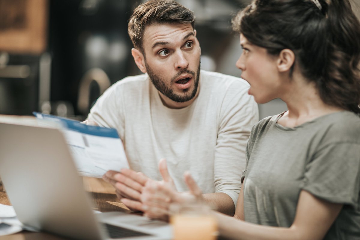 Young couple looking at each other in stunned unpleasant surprise.