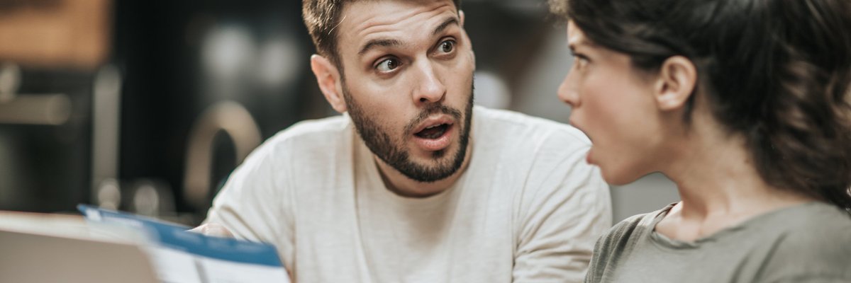 Young couple looking at each other in stunned unpleasant surprise.