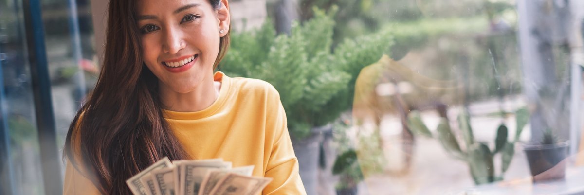 Woman smiling holding cash.
