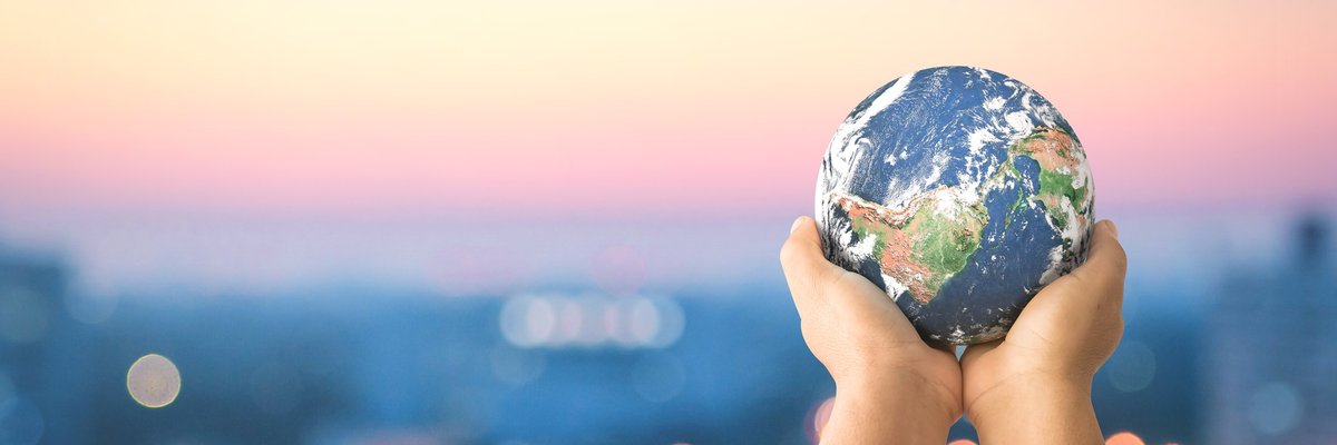 A pair of hands raising forth a small-scale model of planet Earth.