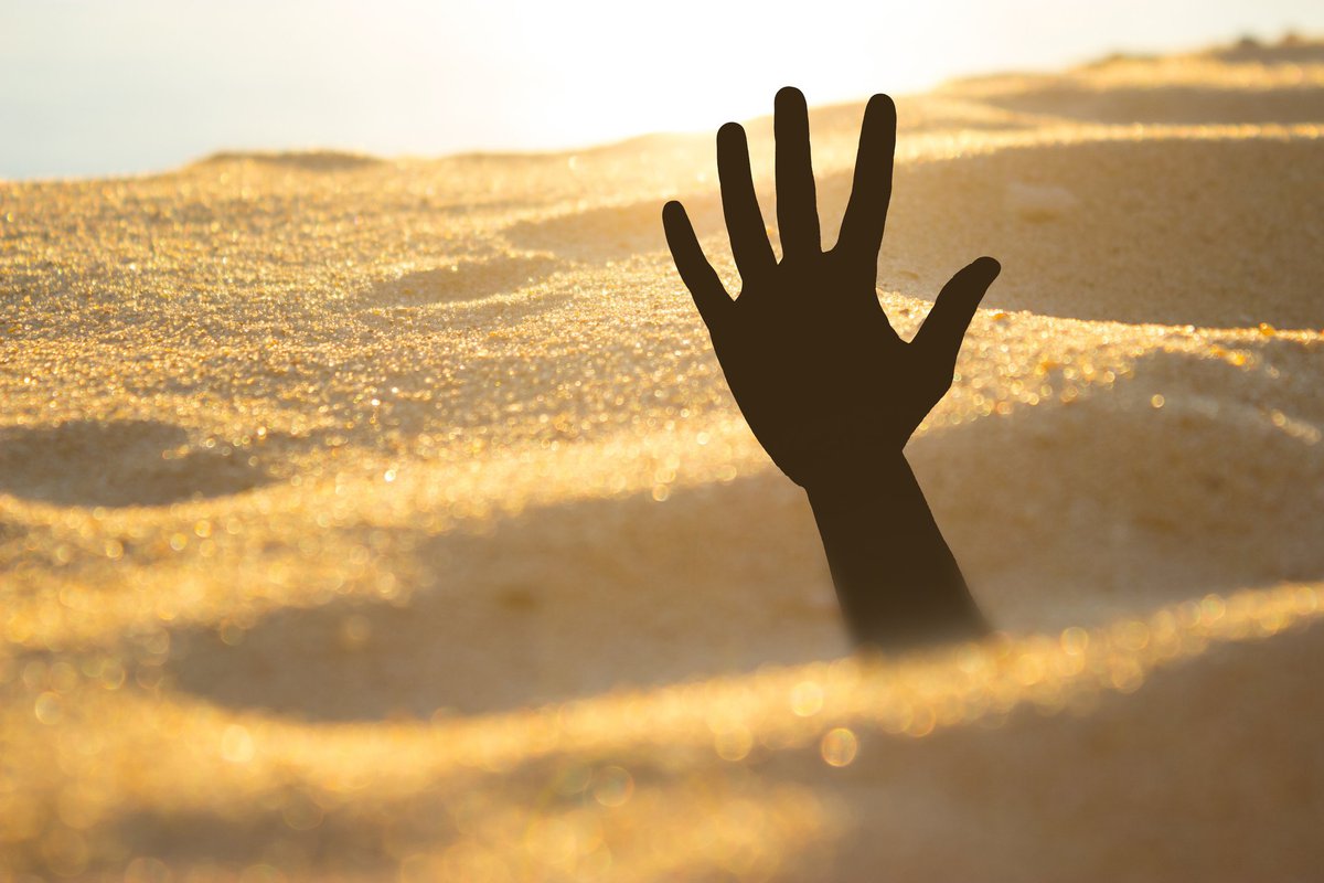 Hand reaching out from quicksand.