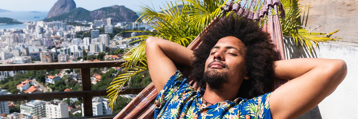 Person relaxing on hammock with luxurious balcony view.