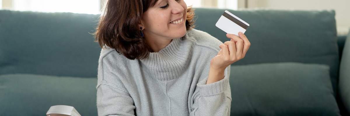 Young woman holding a calculator and a credit card and grinning with satisfaction at the credit card.