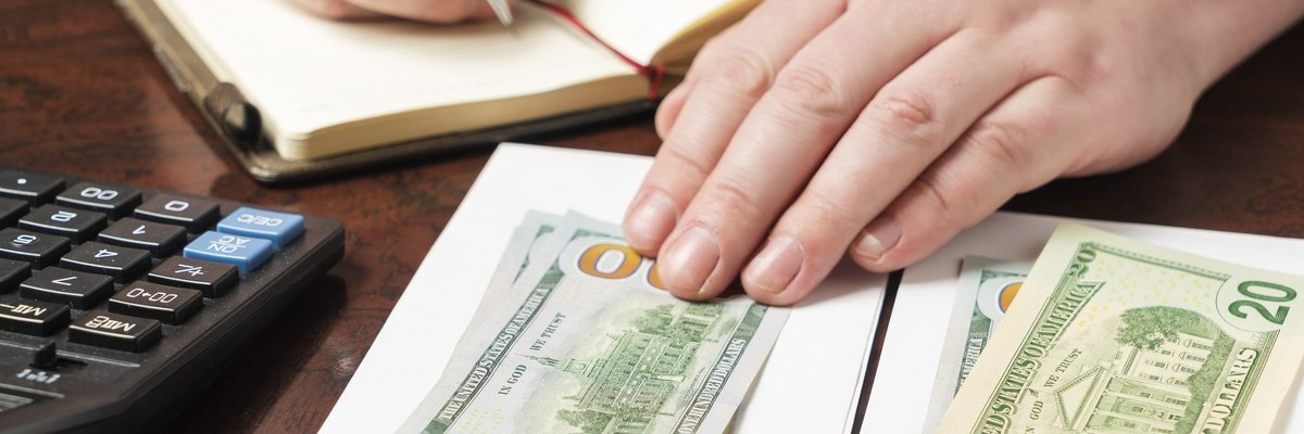 A pair of hands separating stacks of money into envelopes.