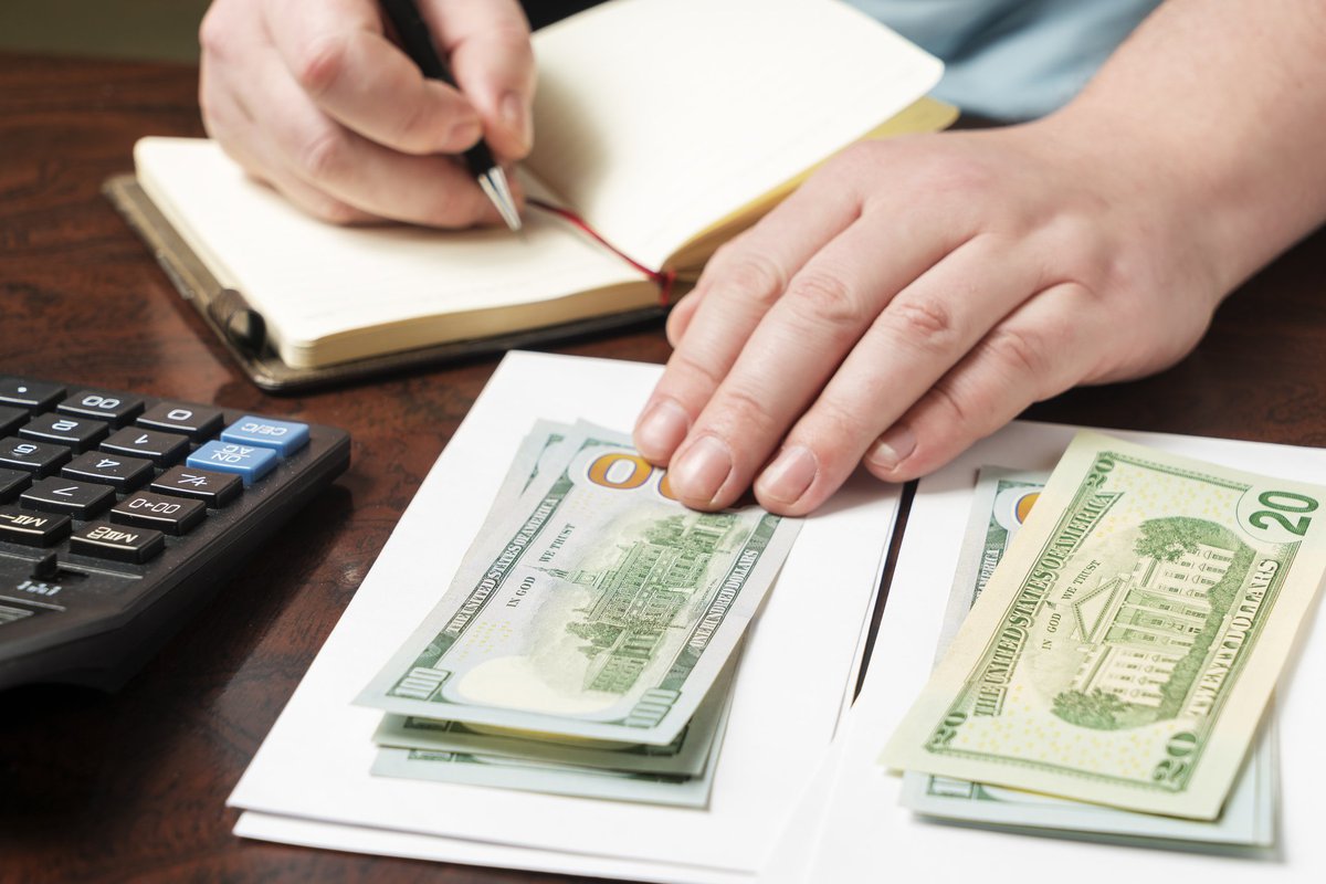 A pair of hands separating stacks of money into envelopes.
