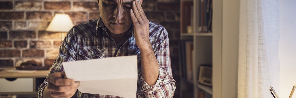Middle-aged man suffering migraine headache caused by bills.