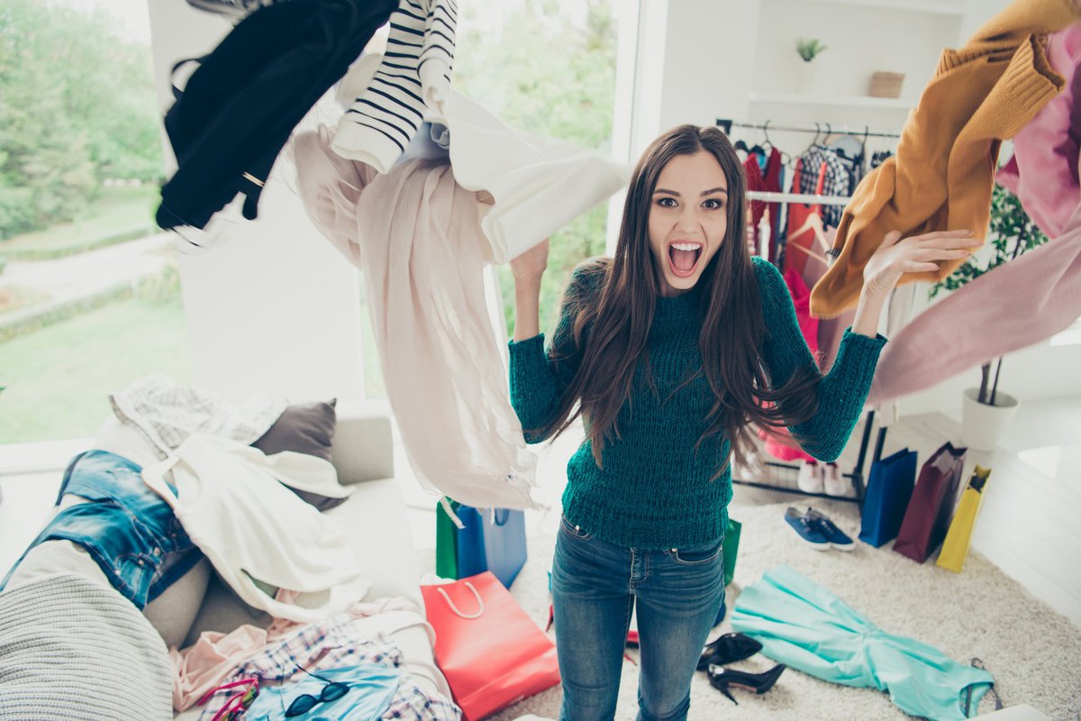 Young woman shrieking as she tosses a bunch of clothes into the air.