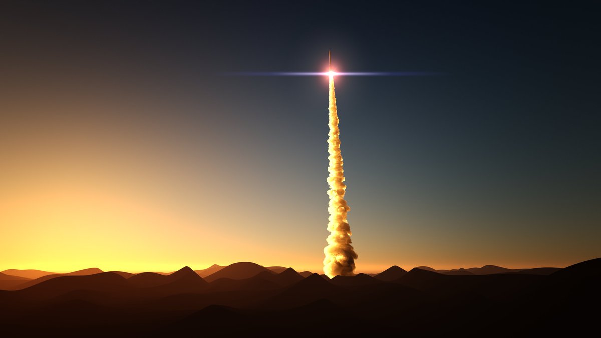 A rocket blasting through a desert sunset into space.