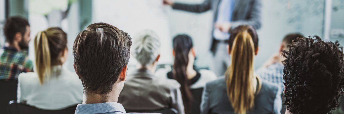 The back view of business people listening to a conference presentation.