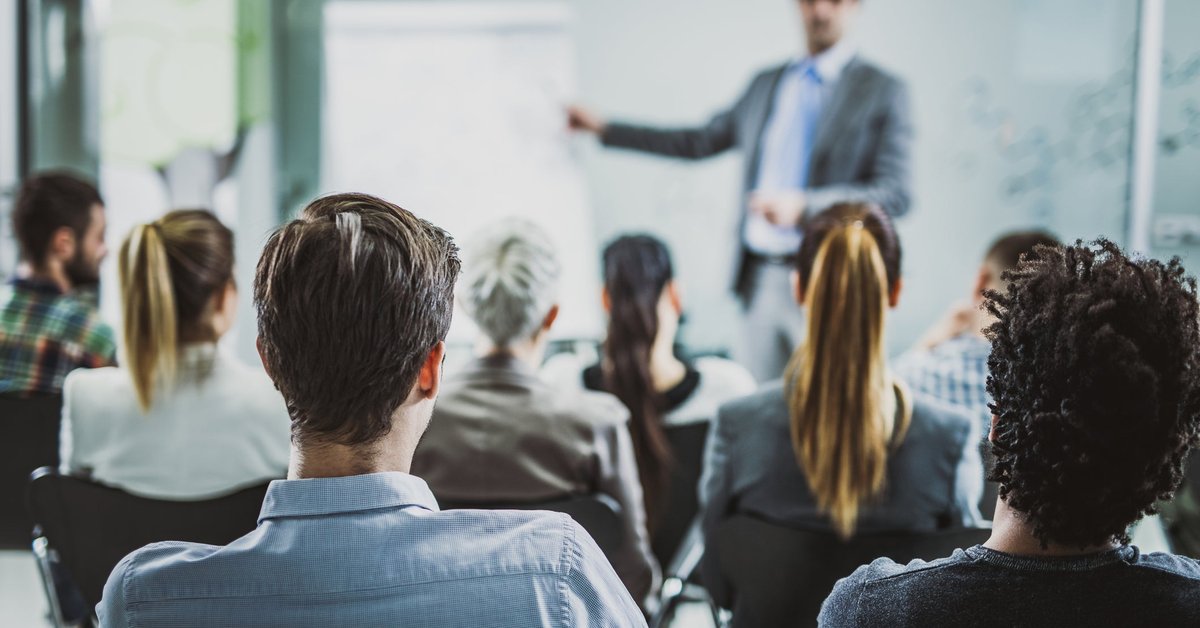 The back view of business people listening to a conference presentation.