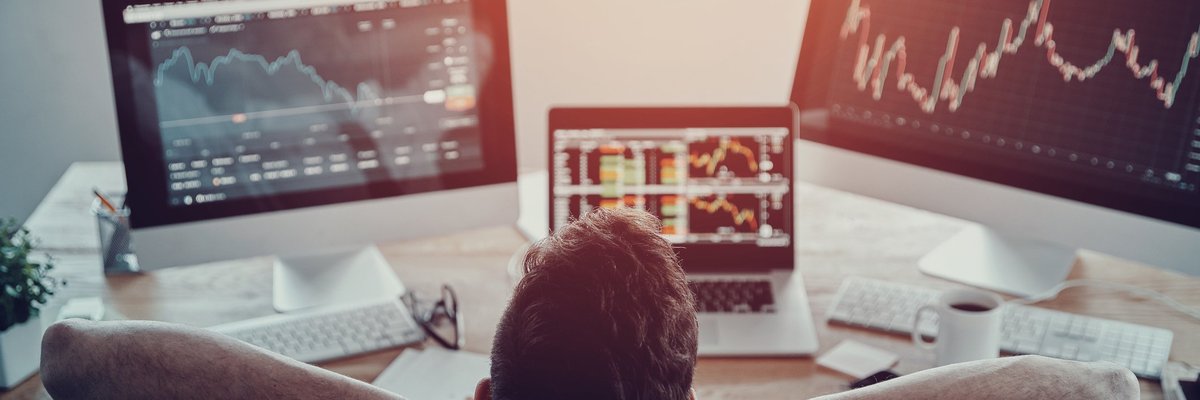 Guy leaning back and monitoring three screens featuring various stock information.