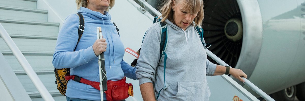 Two people wearing hoodies descend the airplane stairs after a flight.