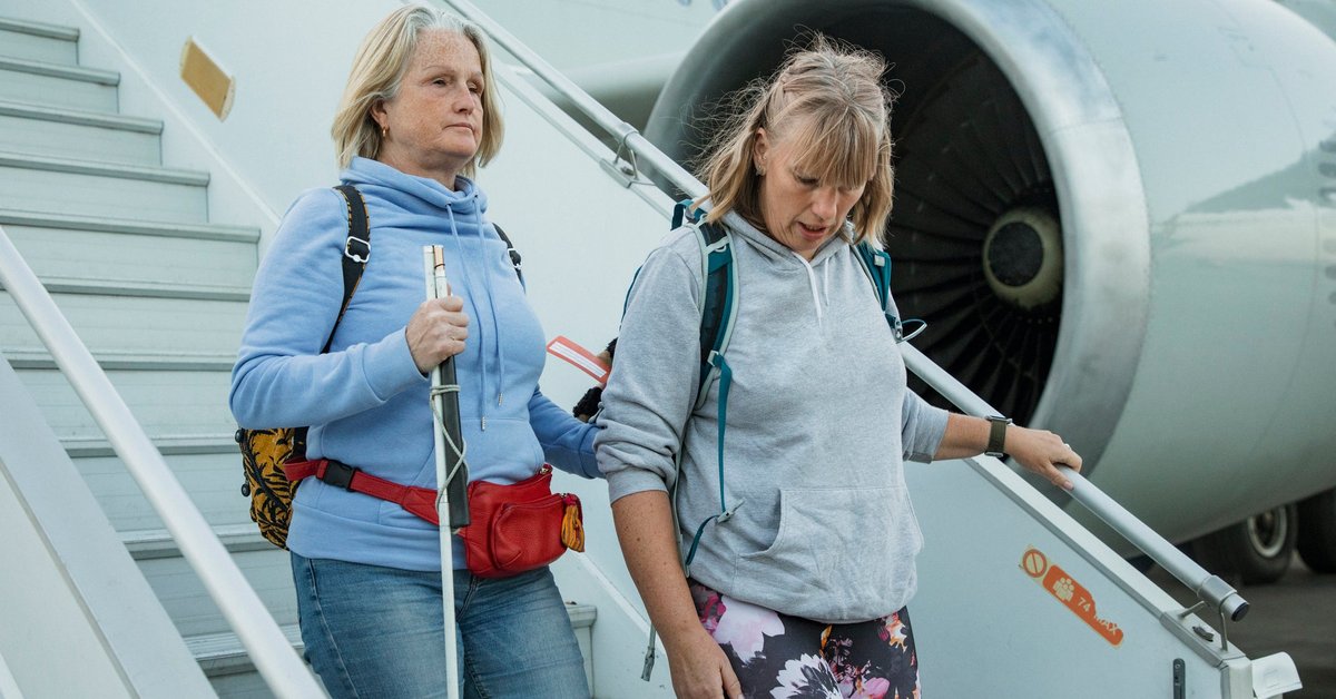 Two people wearing hoodies descend the airplane stairs after a flight.