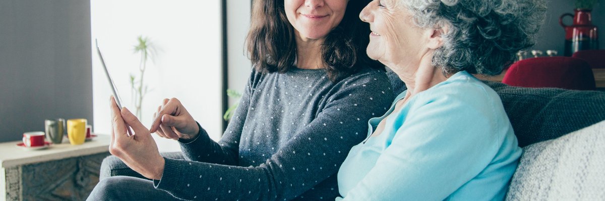 Middle-aged woman showing document to an older woman, possibly her mother.